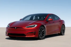 Red Tesla Model S parked under a clear sky, showcasing Elon Musk’s electric vehicle innovation.