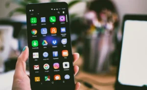 A person holding an Android phone with a dark theme or 'dark mode' enabled, which helps save battery on OLED screens.